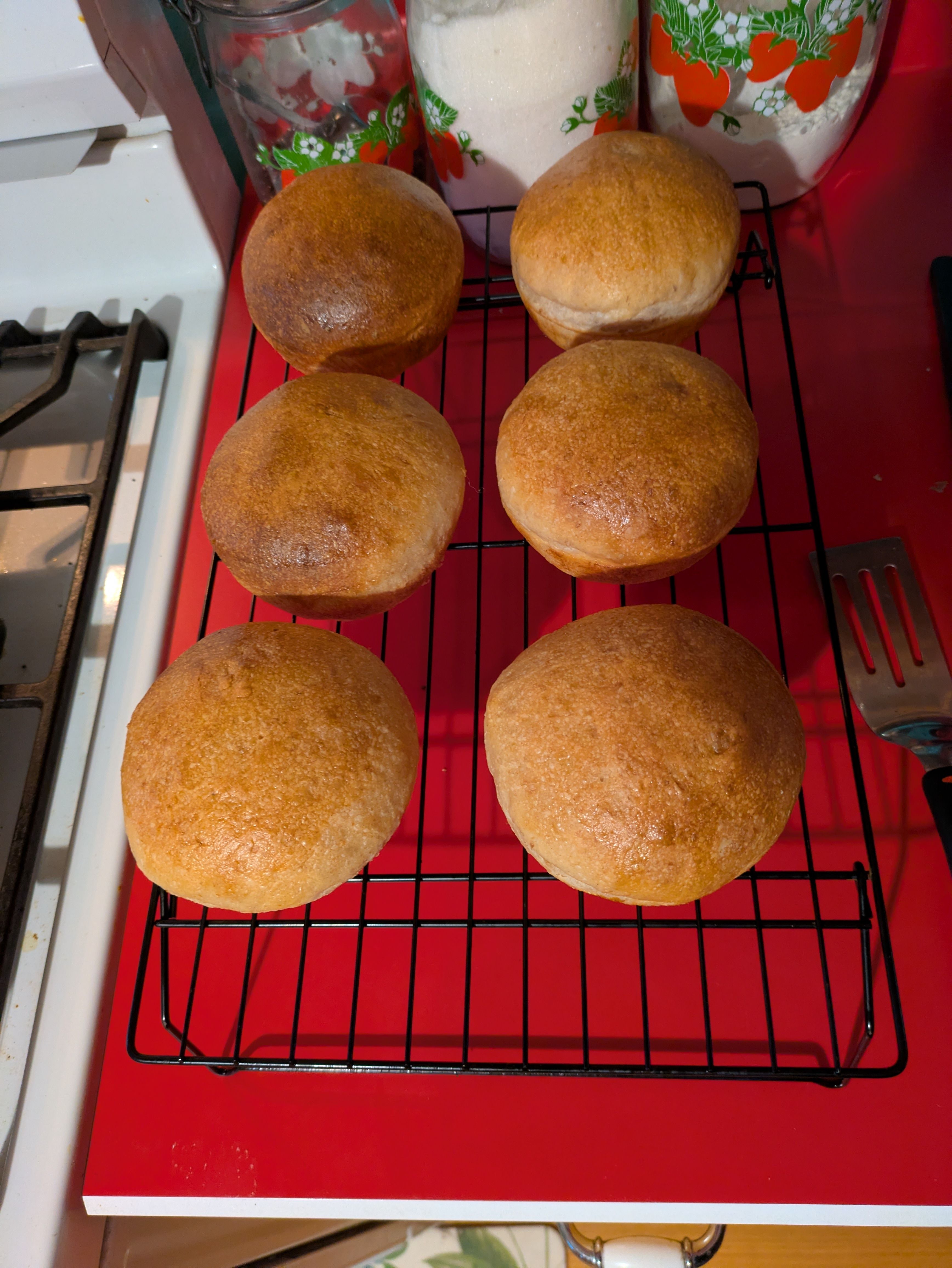 6 Golden brown buns on a black wire cooling rack.