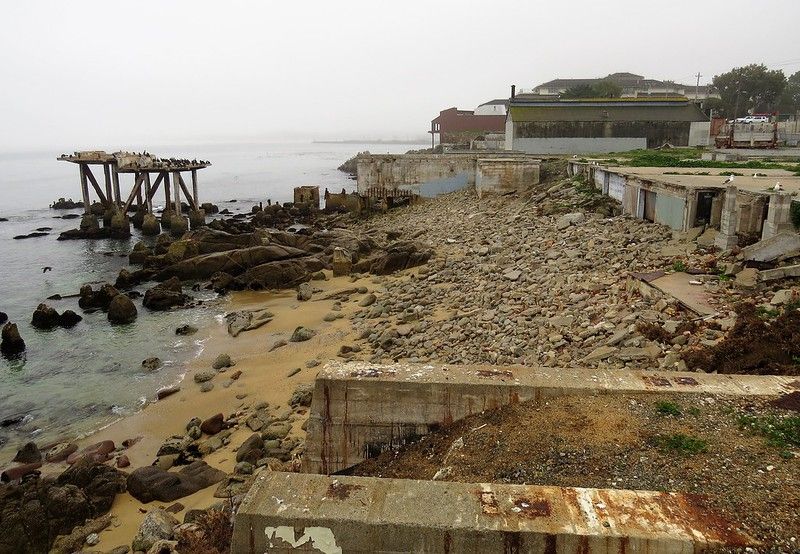 Caption from original reads: 'Monterey, California; while some of the old cannery buildings have been converted to restaurants, tourist shops and hotels, remnants of the canneries and other former businesses along Cannery Row still exist.'