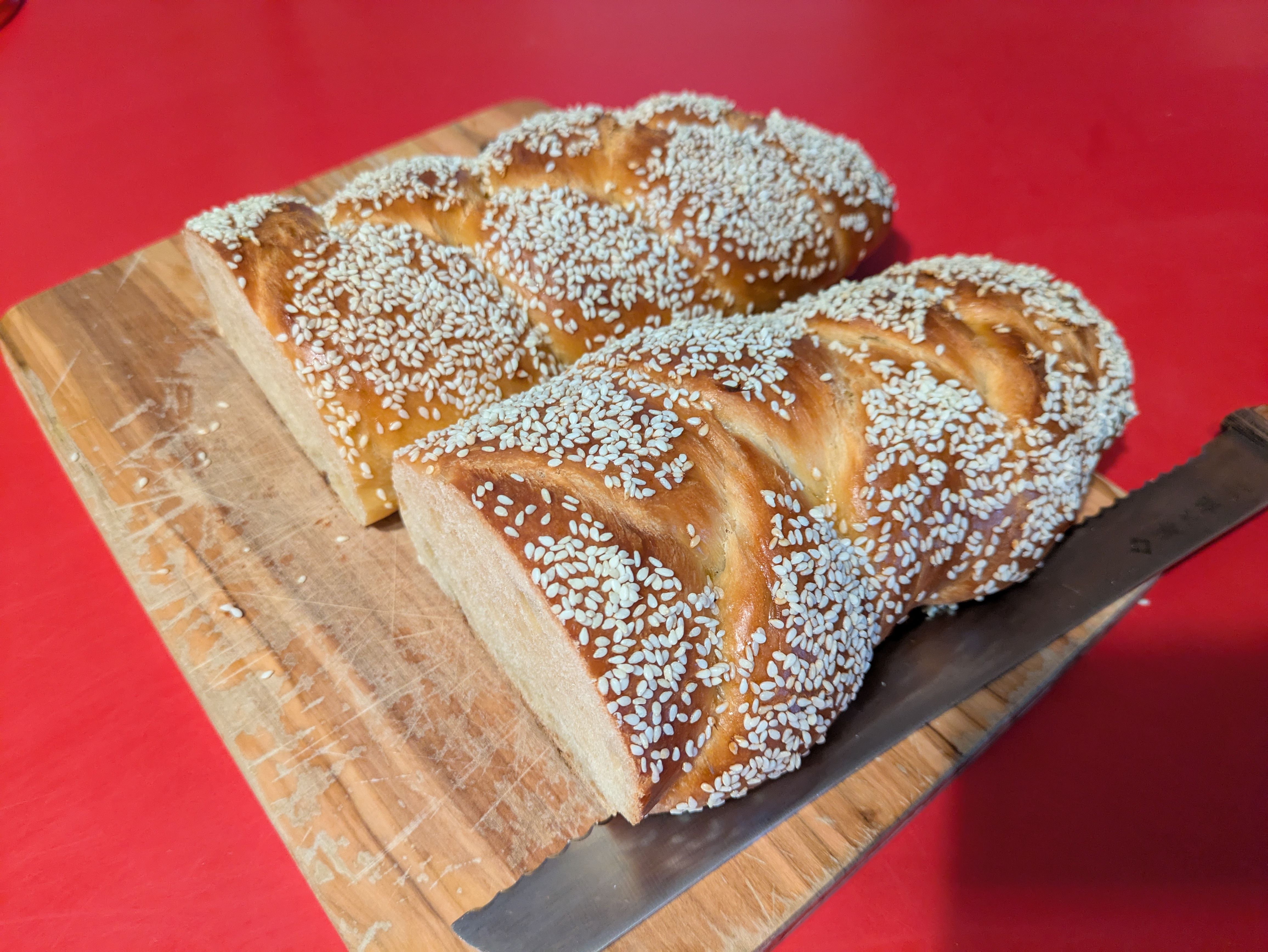 Two halves of a loaf of braided challah side by side on a cutting board.