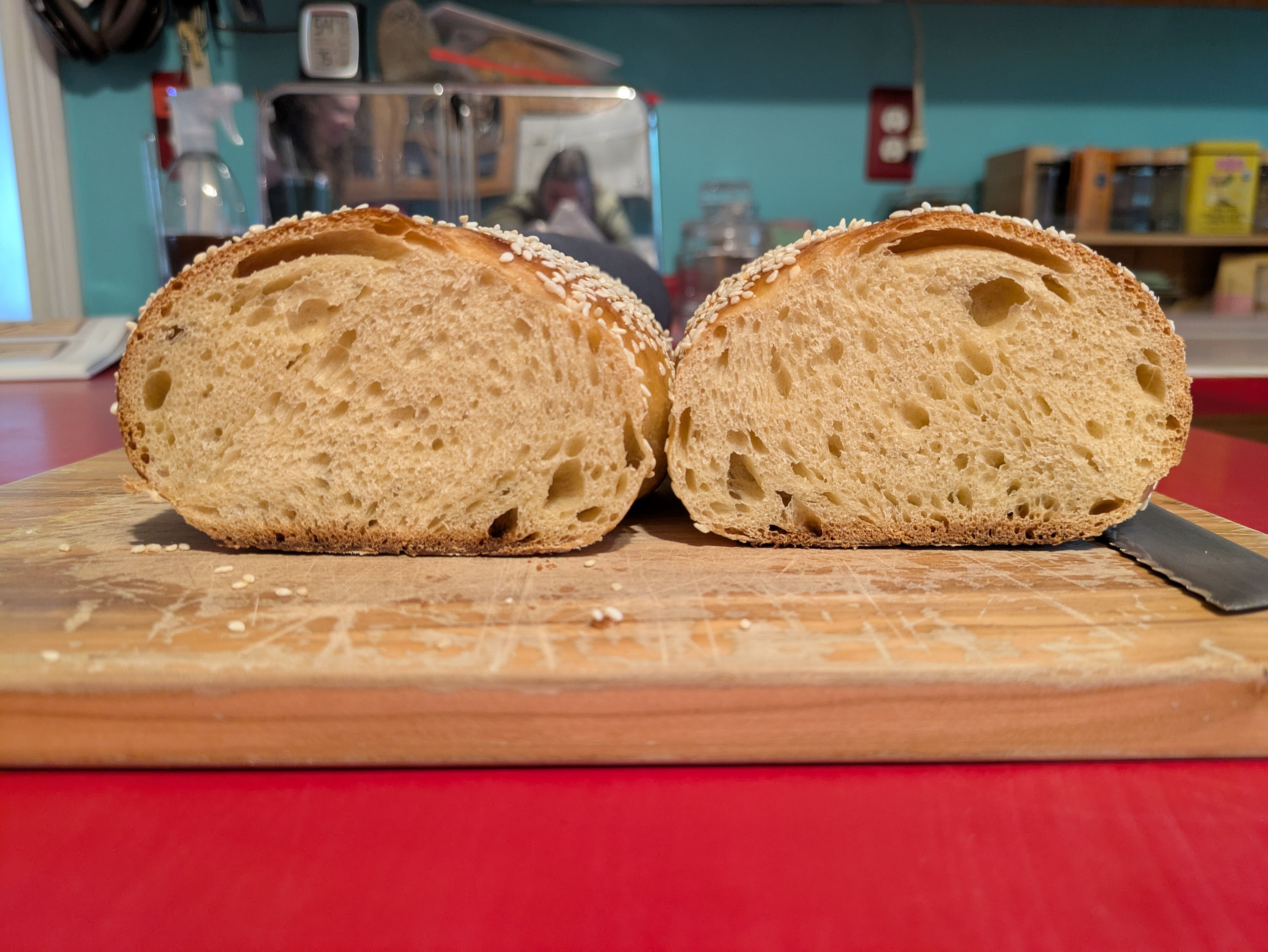 A halved loaf of bread, both sides facing the camera showing the crumb. The bread is on a cutting board.